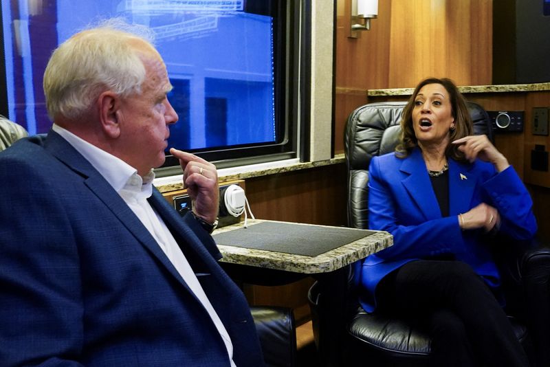 © Reuters. U.S. Democratic vice presidential candidate Minnesota Governor Tim Walz and Democratic presidential candidate and U.S. Vice President Kamala Harris talk at the campaign bus, as Harris and her running mate Walz make a four-stop bus tour of western Pennsylvania before heading to Chicago for the Democratic National Convention, in Rochester, Pennsylvania, U.S., August 18, 2024. REUTERS/Kevin Lamarque