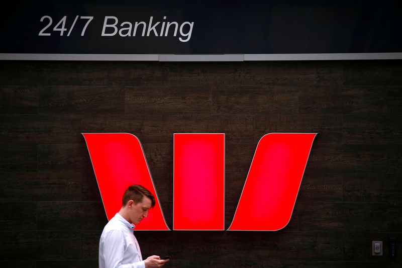 © Reuters. FILE PHOTO: A pedestrian looks at his phone as he walks past a logo for Australia's Westpac Banking Corp outside a branch in downtown Sydney, Australia November 5, 2018. REUTERS/David Gray/File Photo