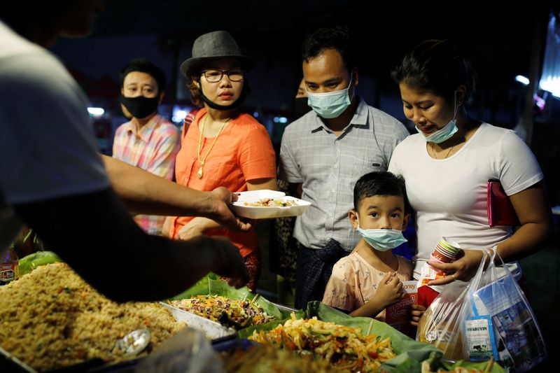 © Reuters. ẢNH TẬP TIN: Một gia đình đeo khẩu trang bảo vệ mua thực phẩm tại một khu chợ ở Yangon, Myanmar, ngày 3 tháng 2 năm 2020. REUTERS/Ann Wang/Ảnh tập tin