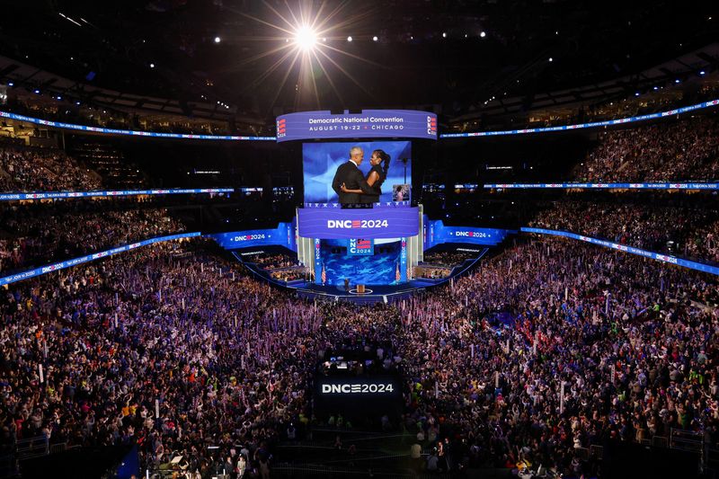 &copy; Reuters. Former U.S. first lady Michelle Obama embraces her husband, former U.S. President Barack Obama, on stage before his speech during Day 2 of the Democratic National Convention (DNC) in Chicago, Illinois, U.S., August 20, 2024. REUTERS/Mike Segar     TPX IMA