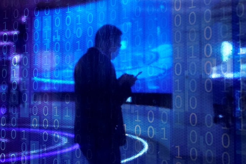 © Reuters. FILE PHOTO: A man looking at his phone is seen through a digitally decorated glass. REUTERS/Aly Song/File Photo