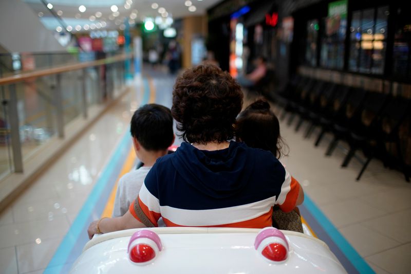 &copy; Reuters. FILE PHOTO: A person sits in a toy car with children at a shopping mall in Shanghai, China June 1, 2021. REUTERS/Aly Song/File Photo