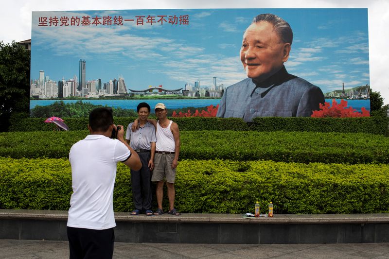 © Reuters. FILE PHOTO: Visitors pose for a picture in front of a photo of late Chinese reformist leader Deng Xiaoping in Shenzhen, south China's Guangdong province, August 19, 2014. REUTERS/Tyrone Siu/File Photo