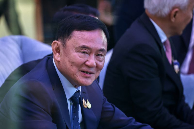 © Reuters. Former Thai Prime Minister Thaksin Shinawatra speaks with businessmen ahead of the 