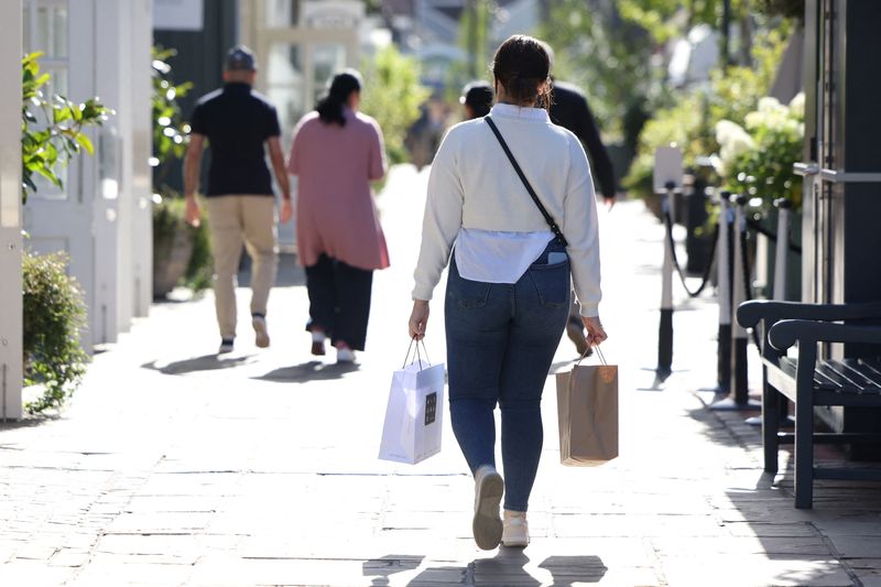 © Reuters. FILE PHOTO: A shopper carries bags while walking through Bicester Village in Oxfordshire, Britain, August 21, 2024. REUTERS/Hollie Adams/File Photo