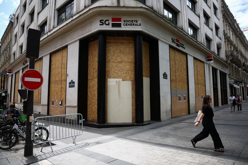 &copy; Reuters. FILE PHOTO: A woman walks past protected windows of a branch of French bank Societe Generale on the Champs-Elysees avenue during the second round of the early French parliamentary election, in Paris, France, July 7, 2024. REUTERS/Guglielmo Mangiapane/File