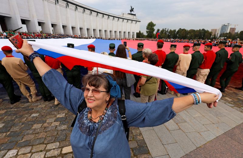 © Reuters. FILE PHOTO: A woman takes part in an event to unfold a large-size Russian state flag during celebrations of National Flag Day in Moscow, Russia August 22, 2024. REUTERS/Maxim Shemetov/File Photo