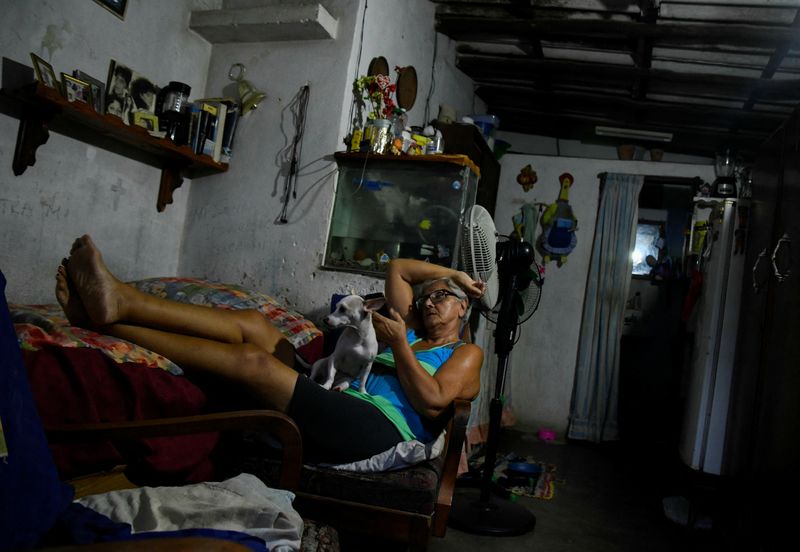 © Reuters. A woman sits with her dog at home during a power caused by breakdowns forcing six plants to go off-line on the grid, according to the state run power company, in Matanzas, Cuba August 22, 2024. REUTERS/Norlys Perez