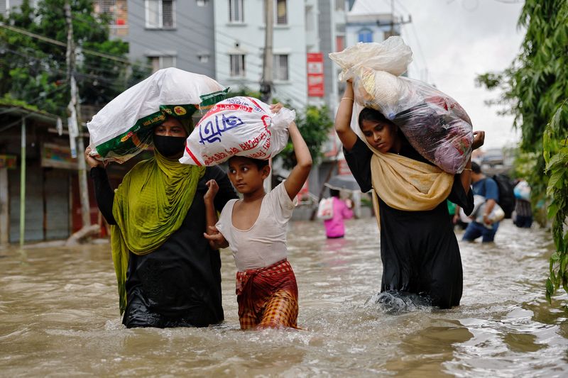 © Reuters. People wade through water as they carry relief supplies amid severe flooding in Feni, Bangladesh, August 25, 2024. REUTERS/Mohammad Ponir Hossain     TPX IMAGES OF THE DAY