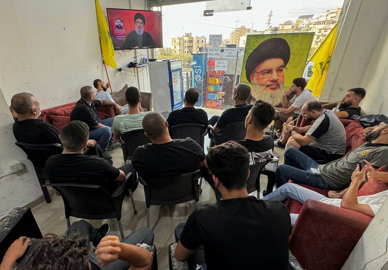 © Reuters. People watch Lebanon's Hezbollah leader Sayyed Hassan Nasrallah delivering a televised address, as they sit at a cafe in Sidon, Lebanon August 25, 2024. REUTERS/Hassan Hankir