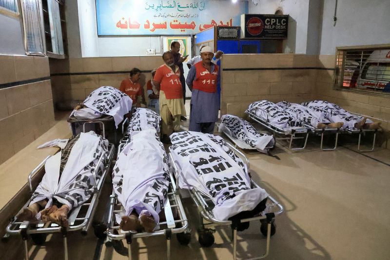 &copy; Reuters. Volunteers stand near the covered bodies of passengers, who were killed after a bus overturned on the Makran Coastal Highway, at the Edhi Foundation morgue in Karachi, Pakistan August 25, 2024. REUTERS/Akhtar Soomro