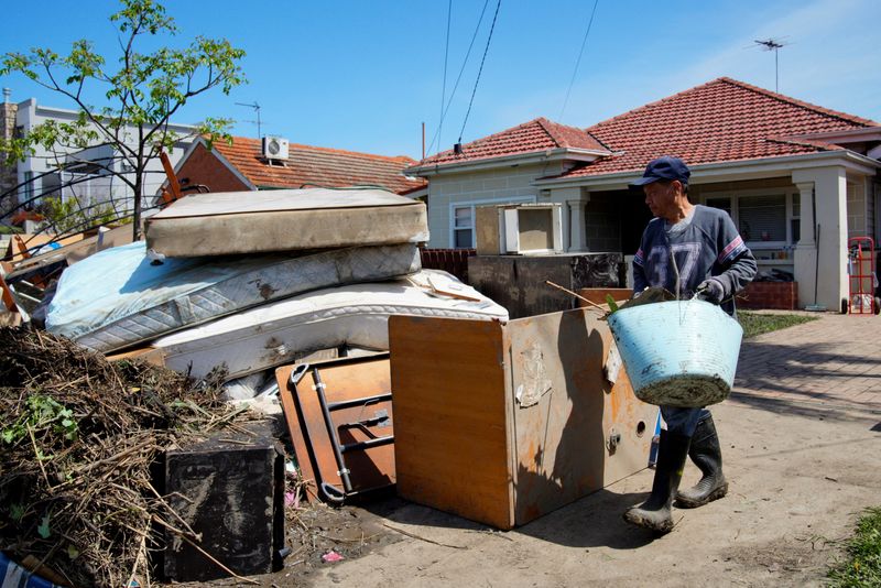 © Reuters. FILE PHOTO: Local resident Van Tran cleans up outside his damaged home following severe flooding in the Maribyrnong suburb of Melbourne, Australia, October 17, 2022.  REUTERS/Sandra Sanders/File Photo