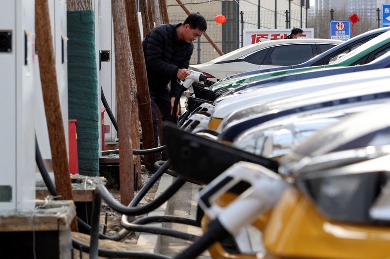 © Reuters. FILE PHOTO: A man holds a charging plug to charge a car at a Smart Charge electric vehicle (EV) charging station in Beijing, China February 2, 2024. REUTERS/Florence Lo/File Photo