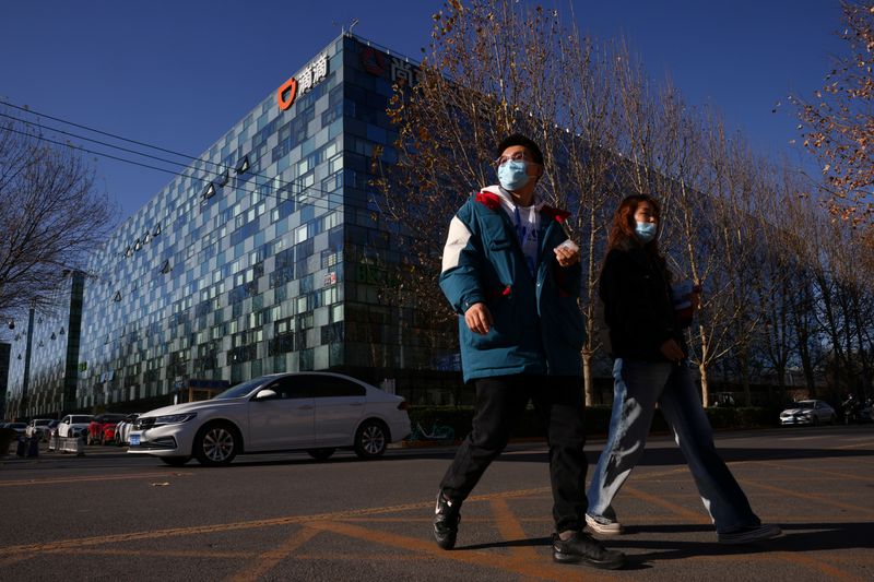 © Reuters. People walk past the headquarters of the Chinese ride-hailing service Didi in Beijing, China, December 3, 2021. REUTERS/Thomas Peter/File Photo