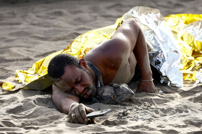 © Reuters. FILE PHOTO: A migrant rests on the sand after arriving in a fiber boat at Las Burras beach in San Agustin, on the island of Gran Canaria, Spain, July 19, 2024. REUTERS/Borja Suarez/File Photo