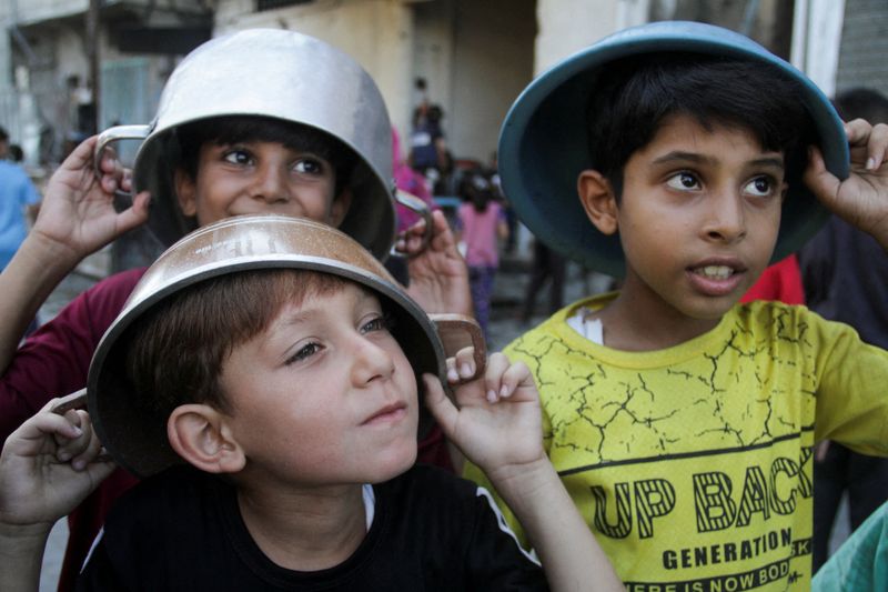 &copy; Reuters. Crianças palestinas esperam para receber comida preparada por um serviço assistencial no norte da Faixa de Gazan14/08/2024nREUTERS/Mahmoud Issa