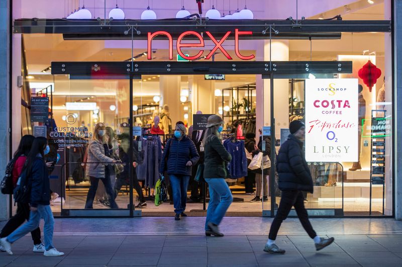 © Reuters. FILE PHOTO: People walk past a store of clothing retailer Next in London, Britain, December 2, 2021. Picture taken December 2, 2021.   REUTERS/May James/File Photo