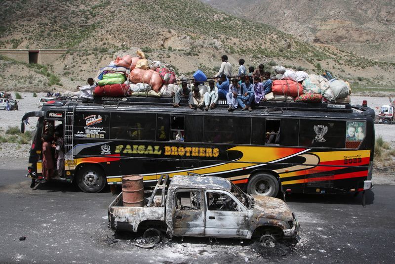 © Reuters. A bus with passengers sitting on the roof with belongings, drives past a damaged vehicle, a day after separatist militants conducted deadly attacks, in Bolan district of Pakistan's restive province of Balochistan, Pakistan August 27, 2024. REUTERS/Naseer Ahmed