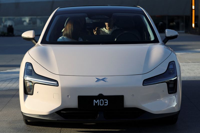 © Reuters. People sit in a MONA M03 electric vehicle (EV), displayed outside the venue of XPeng's launch event, in Beijing, China August 27, 2024. REUTERS/Florence Lo