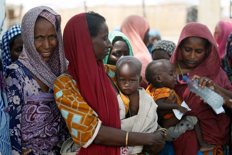 © Reuters. FILE PHOTO: Women wait with their children under a shed for food rations at a internally displaced persons (IDP) camp on the outskirts of Maiduguri, northeast Nigeria June 6, 2017. REUTERS/Akintunde Akinleye/File Photo