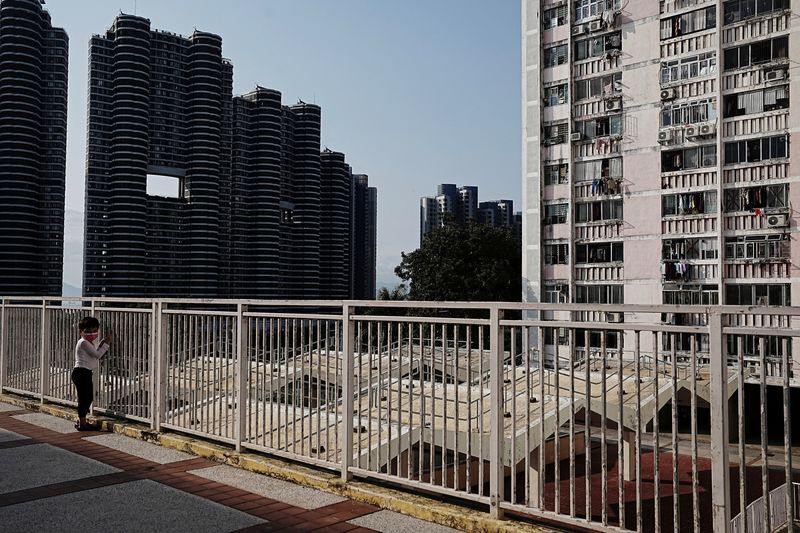 © Reuters. A child stands at a barrier near newly constructed residential buildings next to the Wah Fu public housing estate in Hong Kong, China, February 13, 2023. REUTERS/Lam Yik/File Photo