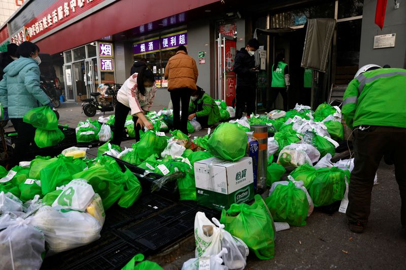 © Reuters. FILE PHOTO: Delivery workers pick up goods at a logistics station of online grocery platform by Meituan in Beijing, China November 23, 2022. REUTERS/Tingshu Wang/File Photo