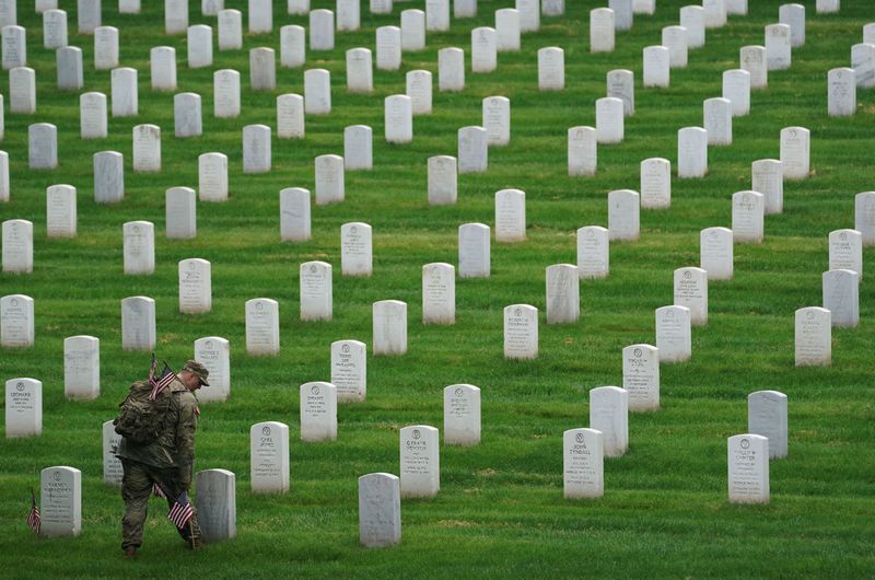 © Reuters. FILE PHOTO: A U.S. Army Old Guard soldier plants flags in front of headstones, Arlington National Cemetery, May 23, 2024. REUTERS/Kevin Lamarque/File Photo