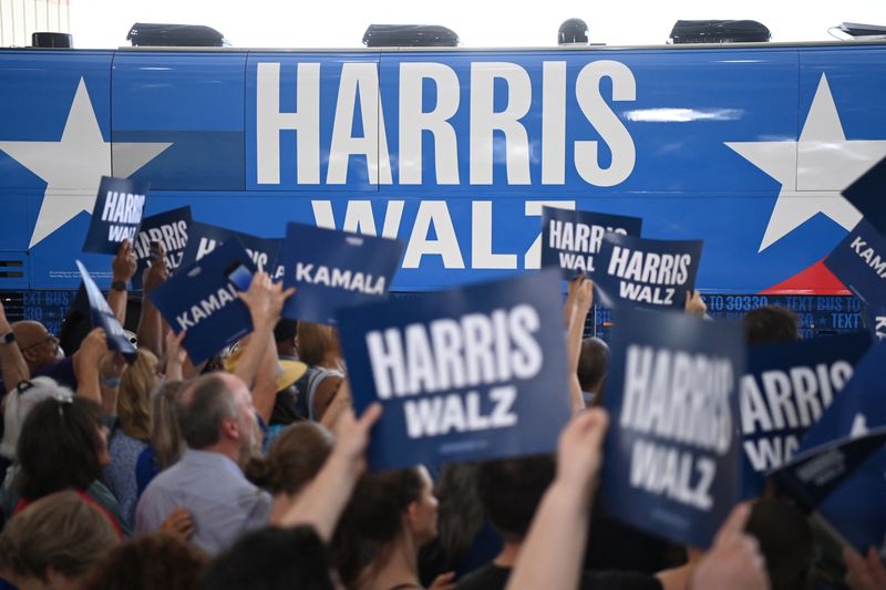 © Reuters. Supporters holding signs wait for the arrival of Democratic presidential candidate and U.S. Vice President Kamala Harris and her vice presidential running mate Minnesota Governor Tim Walz, in Pittsburgh, Pennsylvania, U.S. August 18, 2024. REUTERS/Alan Freed/File Photo