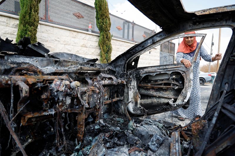 &copy; Reuters. FILE PHOTO: A Palestinian woman inspects a vehicle destroyed during an Israeli settlers' attack in the village of Jeit, near Qalqilya in the Israeli-occupied West Bank August 16, 2024. REUTERS/Raneen Sawafta/File Photo