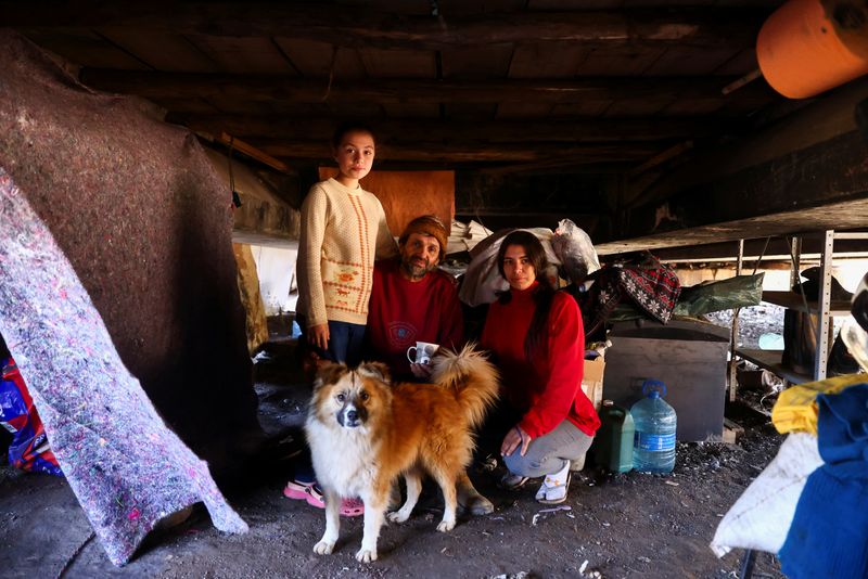 © Reuters. Milton do Nascimento, alongside his wife Gabriela de Freitas and stepdaughter Natalia da Silva, pose inside their temporary housing located under a bridge on BR-290, after their home was hit by the May flood, in Porto Alegre, Rio Grande do Sul, Brazil, August 27, 2024. REUTERS/Diego Vara