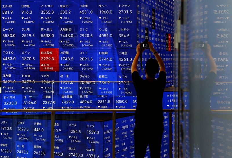 © Reuters. FILE PHOTO: A man takes a photo next to an electronic stock quotation board inside a building in Tokyo, Japan August 2, 2024. REUTERS/Issei Kato/File Photo