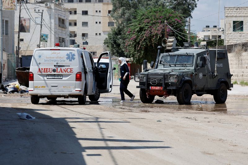 © Reuters. A woman walks during an Israeli raid in Jenin, in the Israeli-occupied West Bank, August 30, 2024. REUTERS/Raneen Sawafta