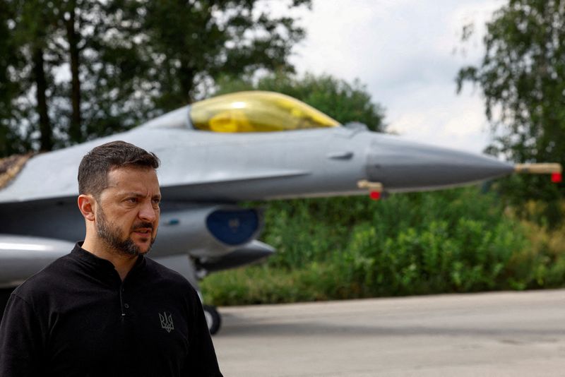 © Reuters. FILE PHOTO: Ukraine's President Volodymyr Zelenskiy speaks to the media in a front of an F-16 fighting aircraft after marking the Day of the Ukrainian Air Forces, amid Russia's attack on Ukraine, in an undisclosed location, Ukraine August 4, 2024. REUTERS/Valentyn Ogirenko/File Photo