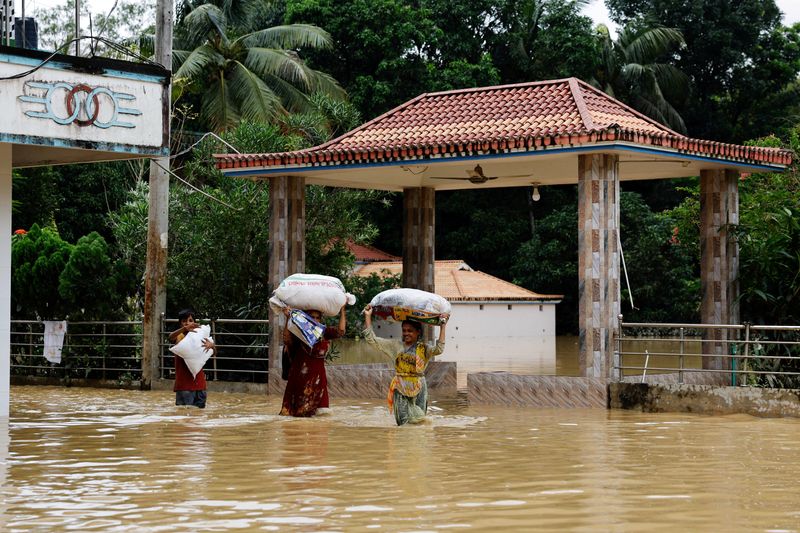 © Reuters. FILE PHOTO: People carrying sacks, wade through flood water, amid severe flooding in the Fazilpur area of Feni, Bangladesh, August 26, 2024. REUTERS/Mohammad Ponir Hossain/File Photo