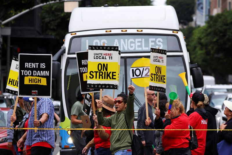 © Reuters. FILE PHOTO: Hotel workers march and protest, while a bus driver waits to cross the road, as they continue their strike in Los Angeles, California, U.S., October 25, 2023. REUTERS/Mike Blake/File Photo