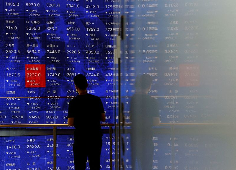 &copy; Reuters. FILE PHOTO: A man stands next to an electronic stock quotation board inside a building in Tokyo, Japan August 2, 2024. REUTERS/Issei Kato/File Photo