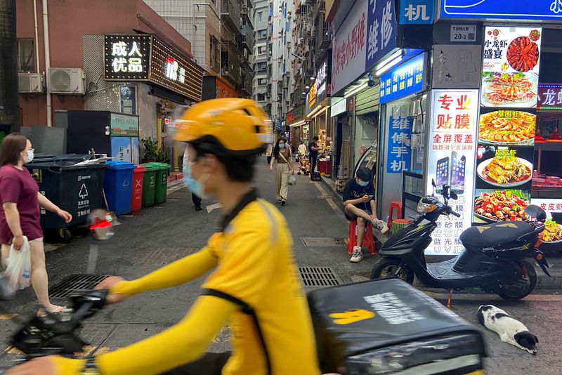 © Reuters. FILE PHOTO: A food delivery worker rides past an urban village in Shenzhen's Futian district, Guangdong province, China May 31, 2022. REUTERS/David Kirton/File Photo