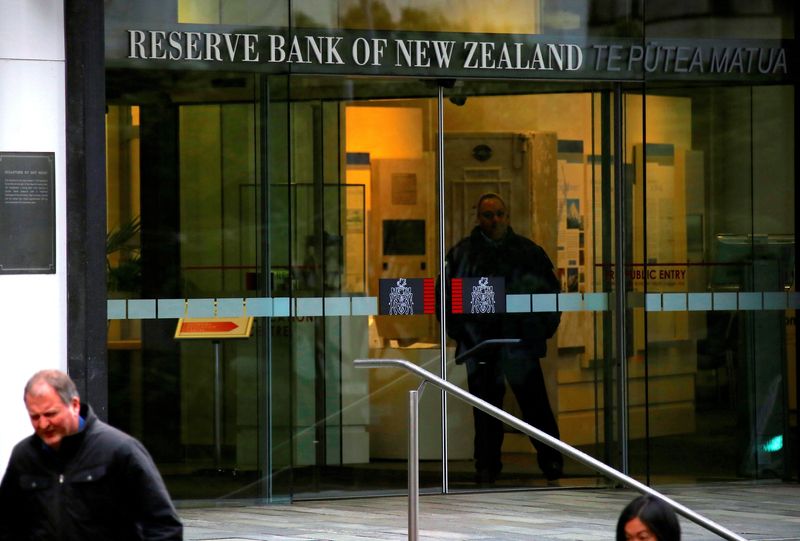 © Reuters. FILE PHOTO: Pedestrians walk past as a security guard stands in the main entrance to the Reserve Bank of New Zealand located in central Wellington, New Zealand, July 3, 2017. Picture taken July 3, 2017.   REUTERS/David Gray/File Photo