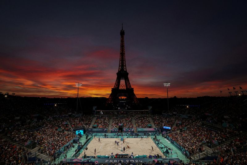 © Reuters. FILE PHOTO: Paris 2024 Olympics - Beach Volleyball - Men's Round of 16 Match - Brazil vs Netherlands (Evandro/Arthur vs van de Velde/Immers) - Eiffel Tower Stadium, Paris, France - August 04, 2024. General view of the Eiffel Tower Stadium shows the Eiffel Tower and the Olympic rings at dusk as the match is on. REUTERS/Paul Childs/File Photo