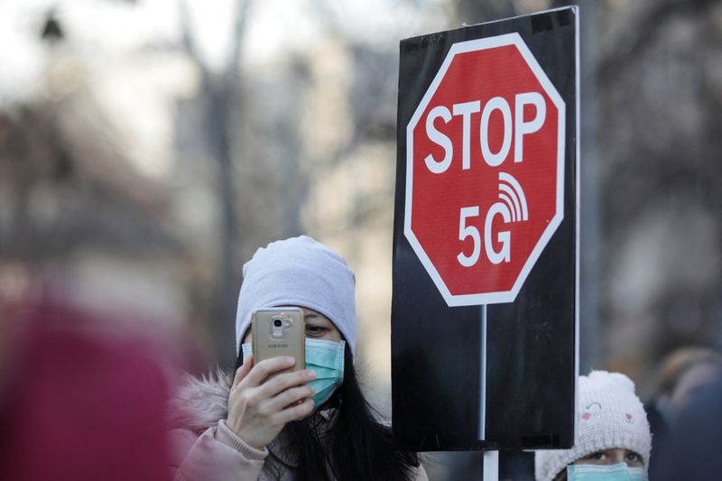 © Reuters. FILE PHOTO: A woman uses her mobile phone while holding a placard reading 