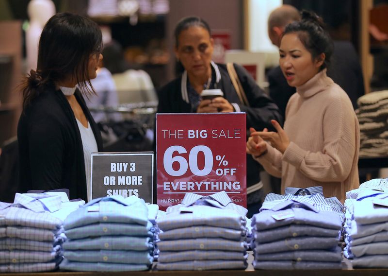 &copy; Reuters. FILE PHOTO: A shop assistant talks to customers in front of a sales sign on display at a retail store in central Sydney, Australia, May 3, 2017. Picture taken May 3, 2017.     REUTERS/Steven Saphore/File Photo