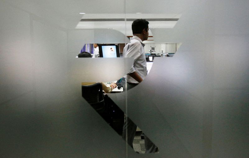 © Reuters. FILE PHOTO: A currency trader is pictured through the symbol for the Indian Rupee on the floor of a trading firm in Mumbai May 31, 2013. REUTERS/Vivek Prakash/File Photo