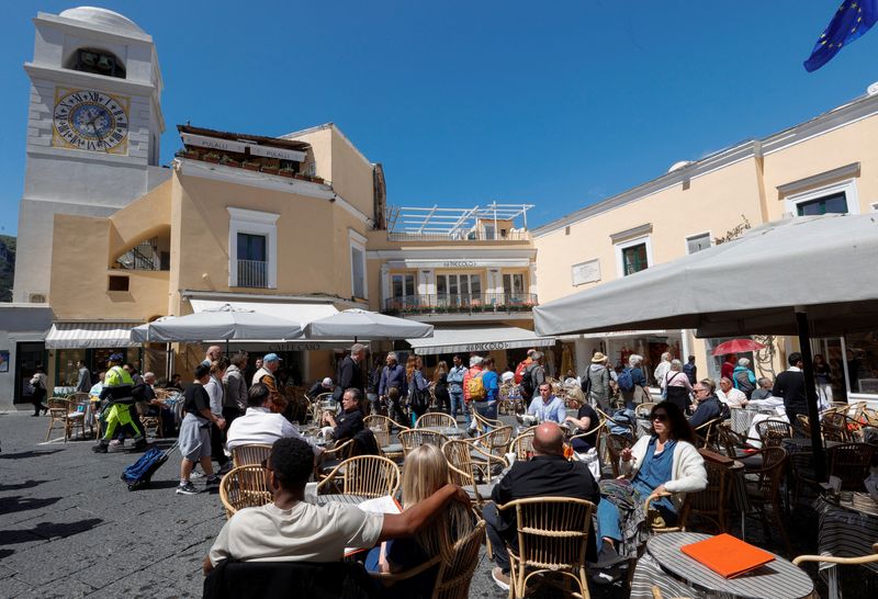 &copy; Reuters. Persone sedute ai tavoli all'esterno di ristoranti e caffè sull'isola di Capri, Italia, 18 aprile 2024. REUTERS/Ciro De Luca