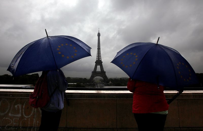 &copy; Reuters. Turisti si proteggono dalla pioggia sotto gli ombrelli davanti alla Torre Eiffel mentre visitano la capitale francese durante le vacanze estive a Parigi, Francia, 19 luglio 2011.   REUTERS/Eric Gaillard