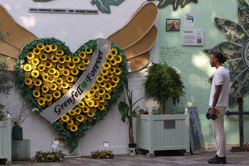 &copy; Reuters. A person views dedications and messages on a wall of condolences near to the covered remains of Grenfell Tower, on the day of the publication of the second report of the UK public inquiry into the deadly 2017 Grenfell fire, in London, Britain, September 4