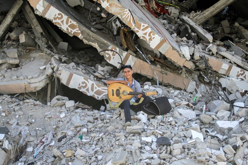 &copy; Reuters. FILE PHOTO: Palestinian teenager Youssef Saad sits on the rubble of his house as he plays oud to bring joy to children, amid Israel-Hamas conflict, in Jabalia refugee camp in the northern Gaza Strip September 2, 2024. REUTERS/Mahmoud Issa/File Photo