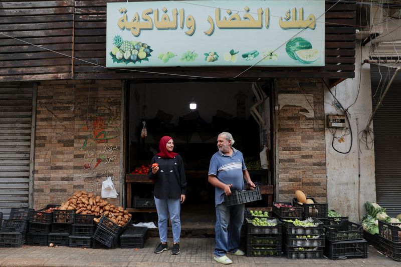 © Reuters. FILE PHOTO: Fruits and vegetable shop owner, Hussein Fakih, and his daughter, Alaa, stand in front of their shop in Bourj Hammoud, Lebanon September 2, 2024. REUTERS/Emilie Madi/File Photo