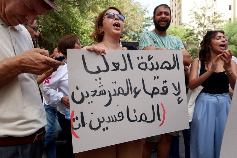 © Reuters. FILE PHOTO: A demonstrator carries a banner during a protest demanding the implementation of a ruling by the administrative court to reinstate three other prominent candidates in the presidential race, near the headquarters of the Electoral Commission in Tunis, Tunisia September 2, 2024. REUTERS/Jihed Abidellaoui/File Photo