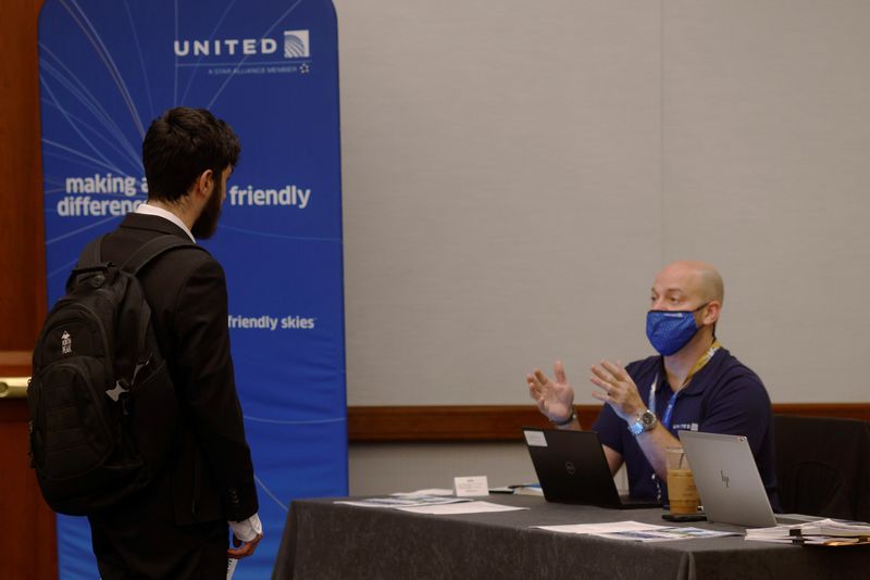 © Reuters. FILE PHOTO: A job seeker talks to a representative from United Airlines at a job fair for airport related jobs at Logan International Airport in Boston, Massachusetts, U.S., December 7, 2021.   REUTERS/Brian Snyder/File Photo