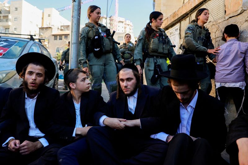 © Reuters. FILE PHOTO: Ultra-Orthodox Jewish men lock their hands during a protest against attempts to draft men from the community, outside a military recruitment office in Jerusalem, August 21, 2024. REUTERS/Ammar Awad/File Photo